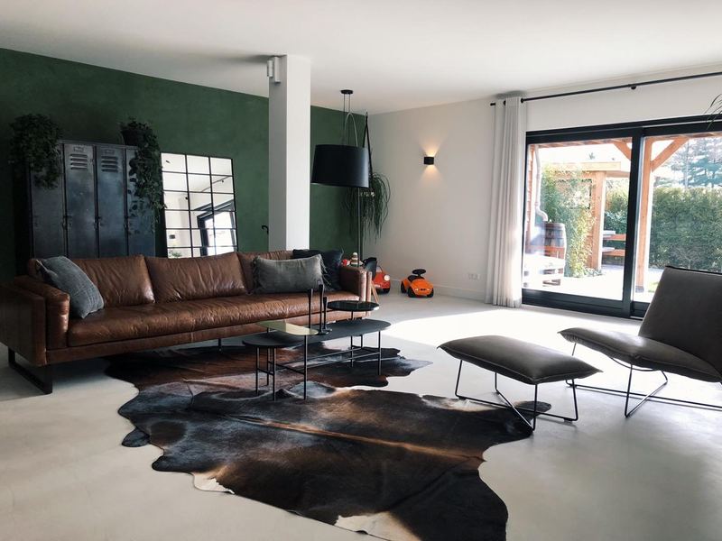Woonkamer met groene accentwand en microtopping vloer