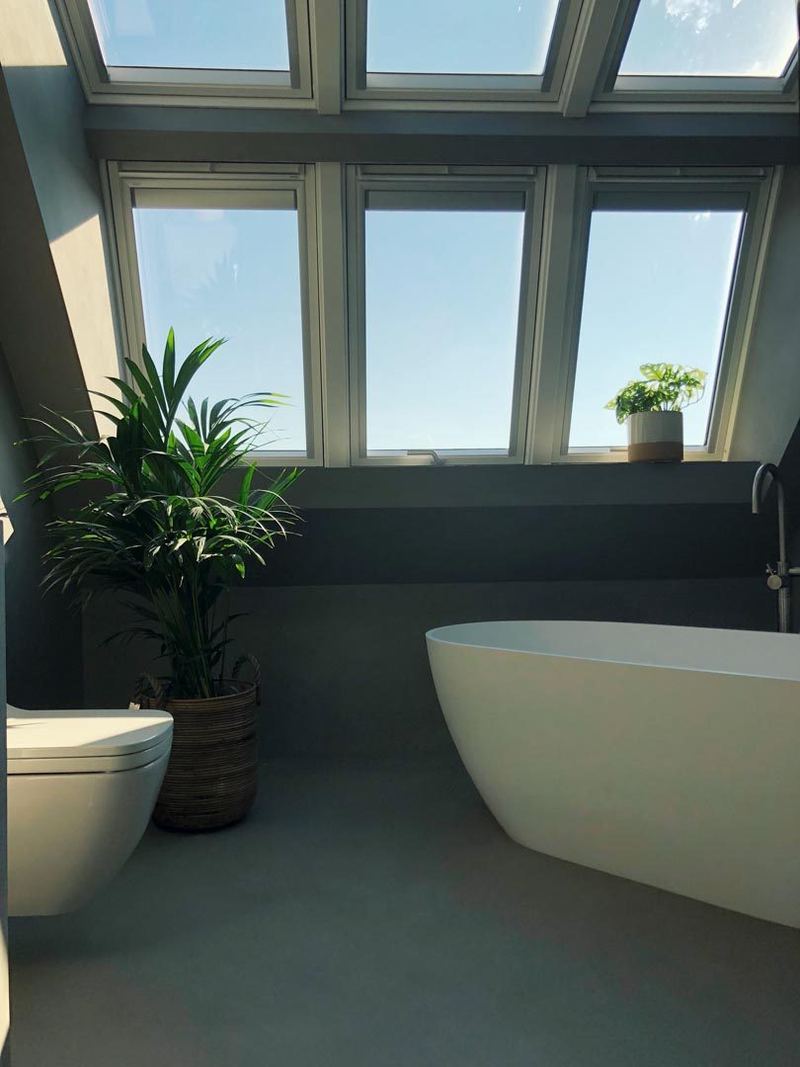 Badkamer met vrijstaand bad onder een rij dakramen