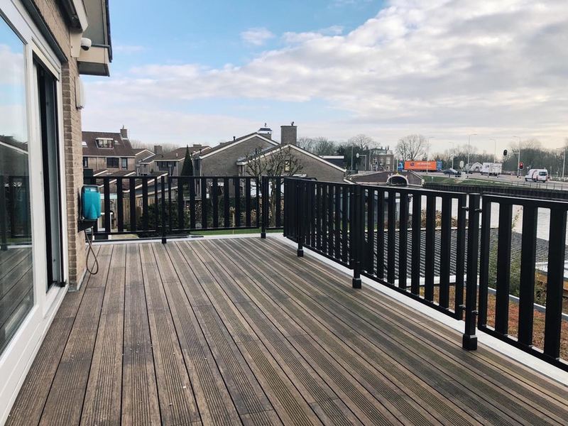 Dakterras met houten vlonder en zwart stalen hek