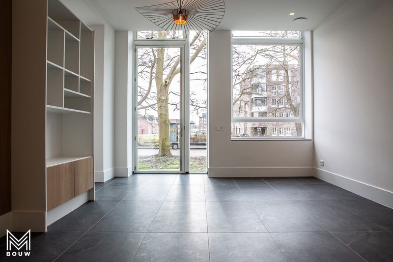 Woonkamer met hoge ramen en ingebouwde kast