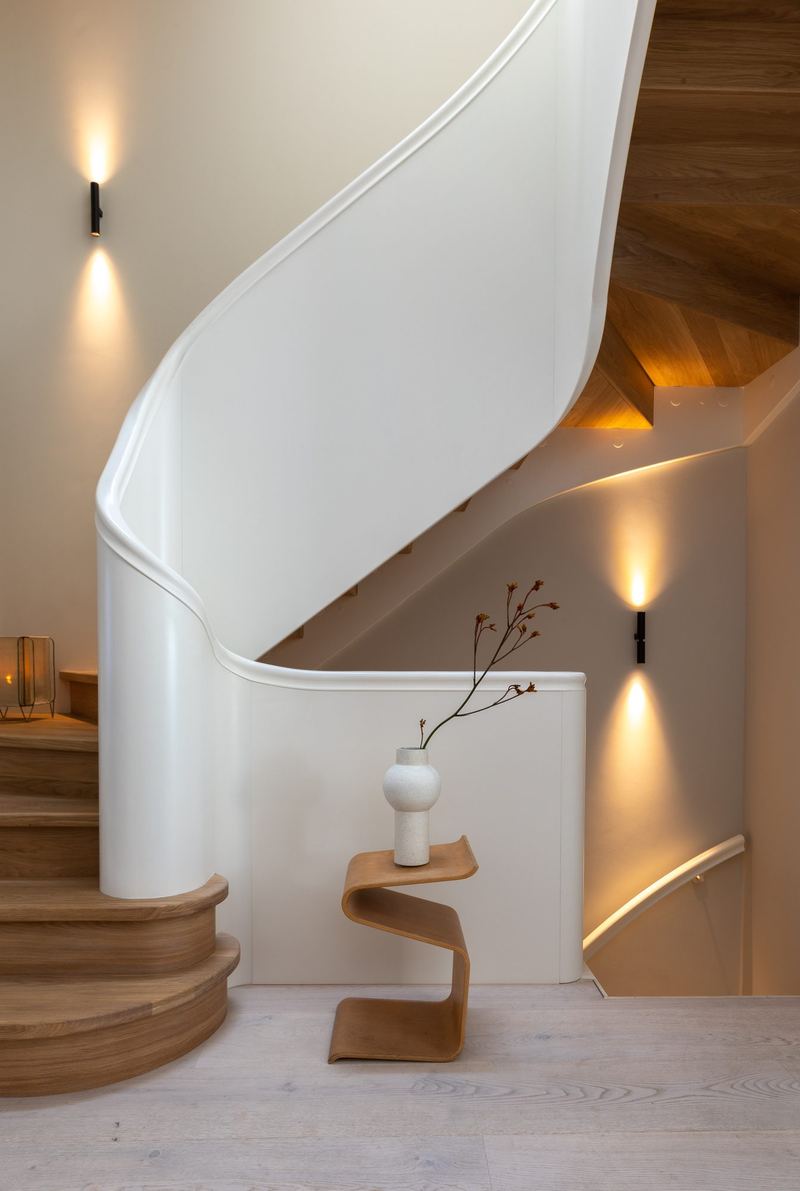 Gebogen witte trap met eiken treden en wandlamp