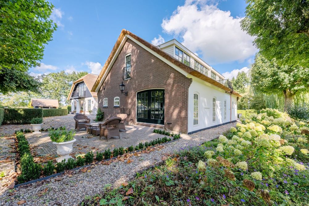 Woonboerderij met rieten kap en terras in de tuin