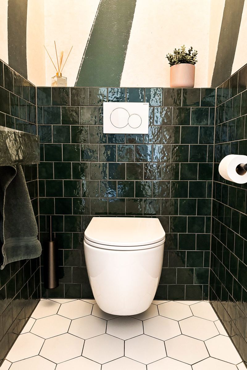 Toilet met donkergroene glanzende tegels en witte zeshoekvloer