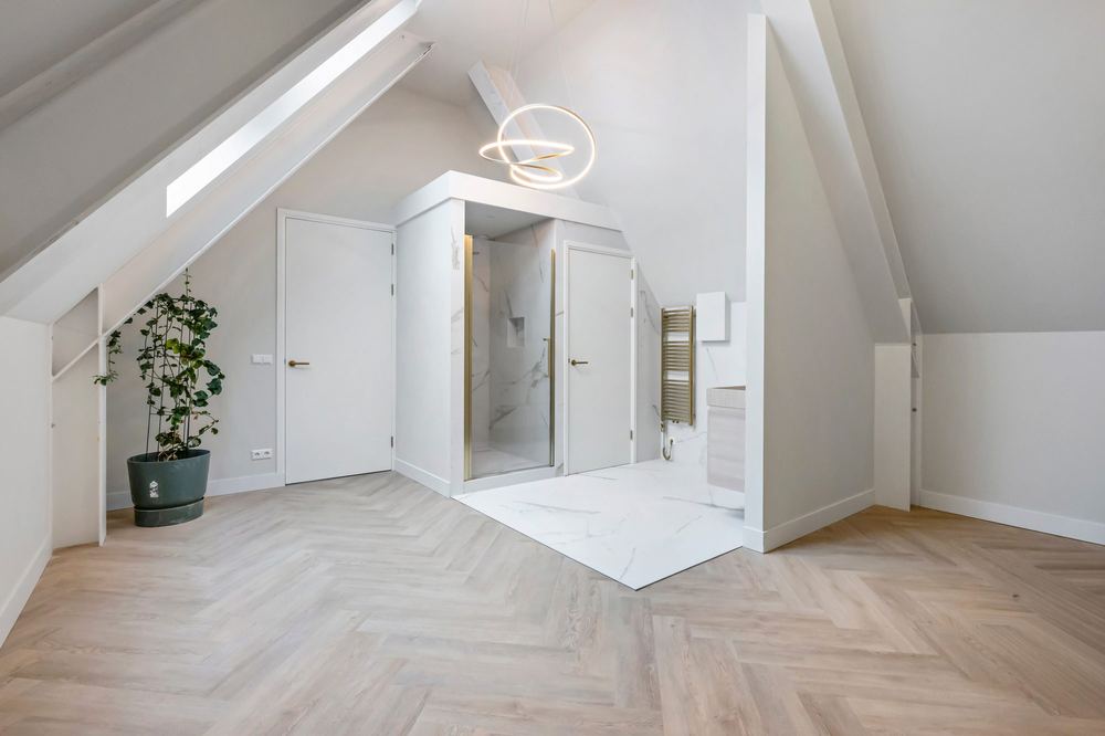 Badkamer onder de kap met douchevolume en visgraatvloer